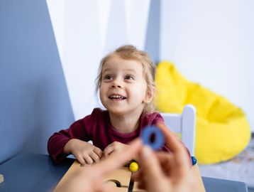 A young girl smiling and looking excited at a colorful object.