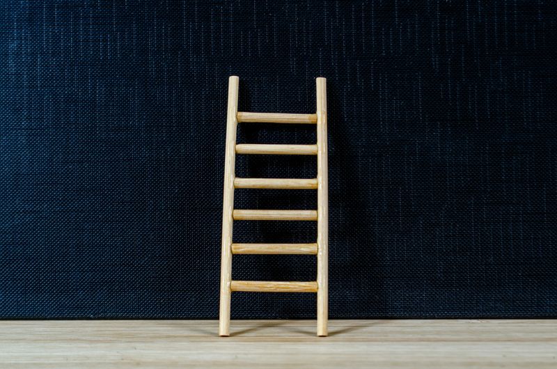 Wooden ladder on dark cover background with customizable space for text or ideas, symbolizing progress, growth mindset, and career advancement concept.