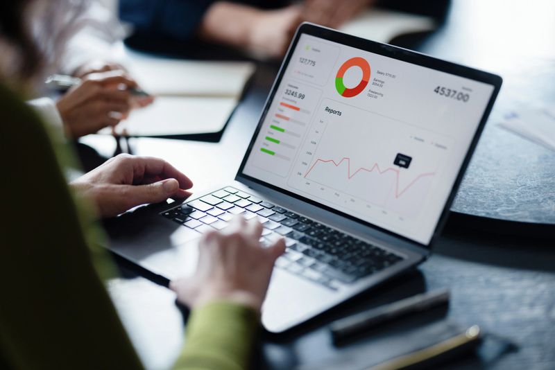 Business team reviews analytics dashboard on a laptop during a collaborative meeting to analyze sales and metrics.