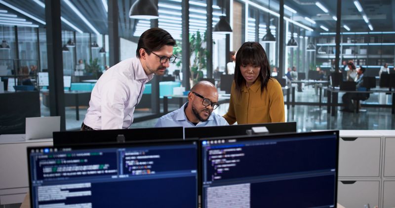 Diverse Team Collaborates In Office, Coding Software And Developing Websites