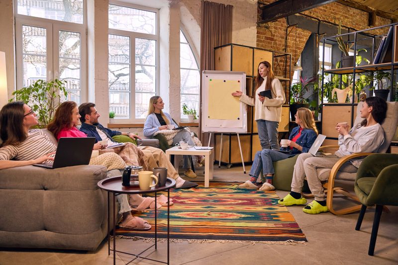 Woman presenting ideas to team during relaxed loft meeting. Concept of leadership, business coaching and collaborative planning in modern startup office.