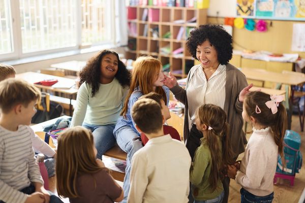 Teacher engaging with happy students in a classroom.