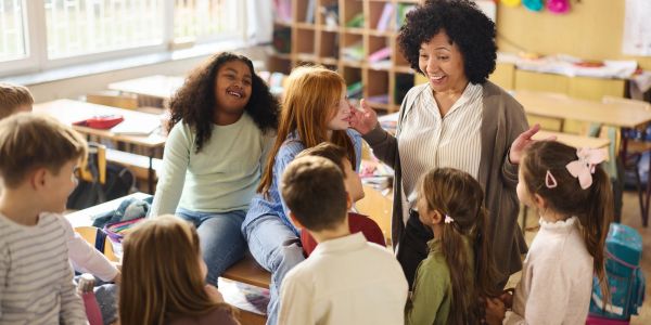 Teacher engaging happily with a group of children in a classroom.