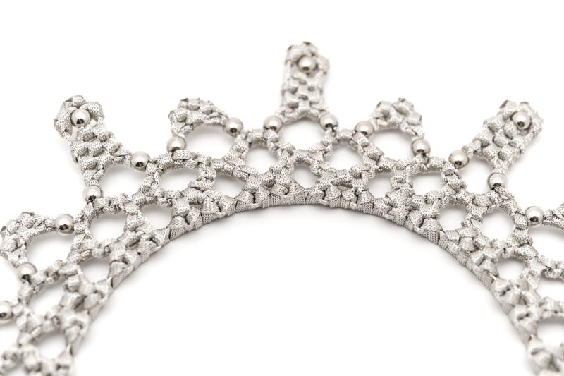 The lace crown features a detailed pattern made of silver material. Beads add texture and dimension. This item is displayed on a white background for clarity.