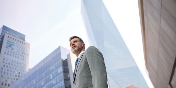 Confident businessman in a suit looking up in a city.