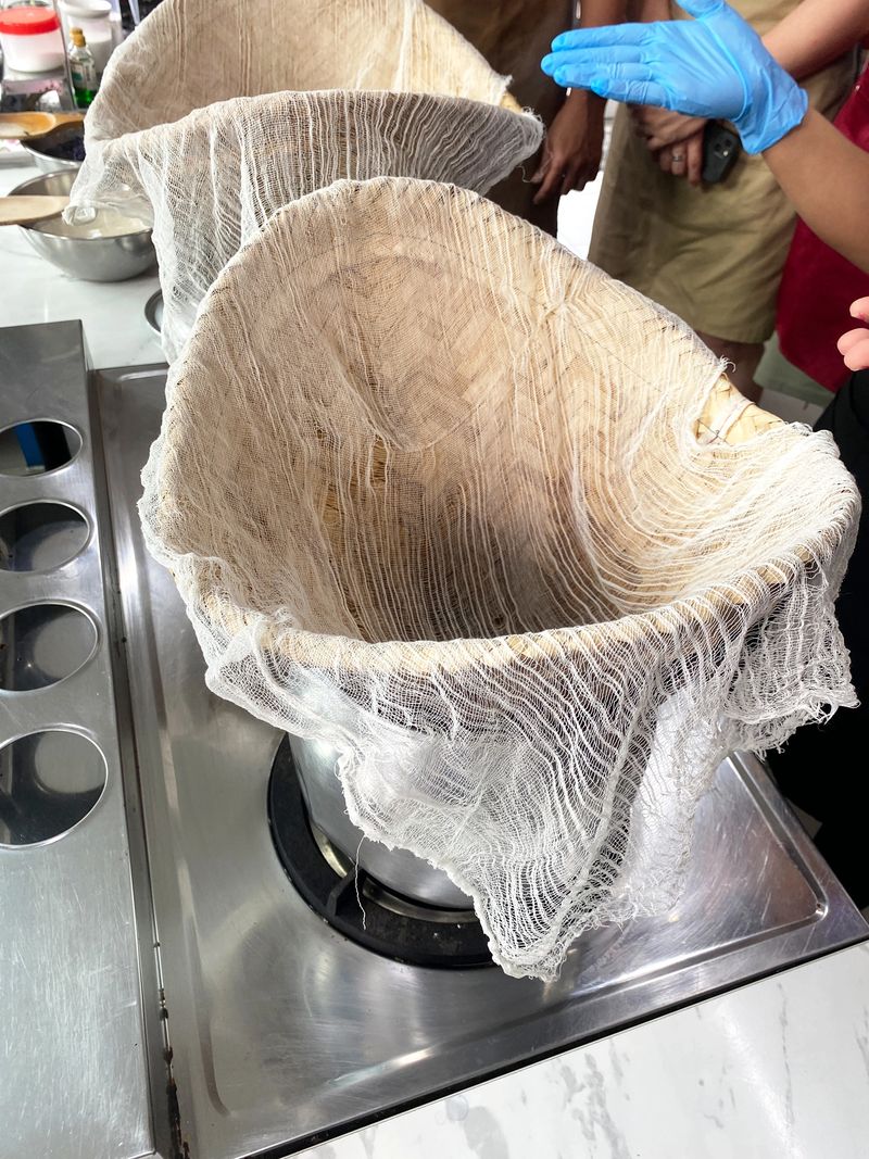 Traditional Thai cooking setup featuring a muslin cloth over a pot, used for preparing mango sticky rice dessert in a contemporary kitchen setting