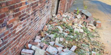 Pile of broken bricks and debris near a brick wall.