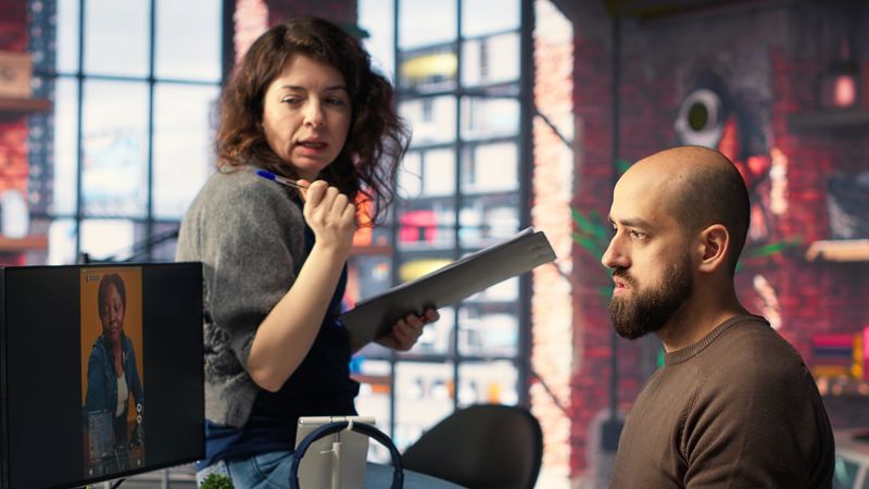 In a tech driven studio, team edits smartphone video footage on a dual monitors setup, applying professional tools for video creation. Targeting algorithm shifts and maximizing engagement. Camera B.
