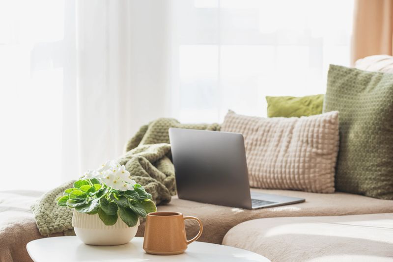 Laptop, Coffee Mug and Flower Pot on Table. Cozy Spring Home Workspace