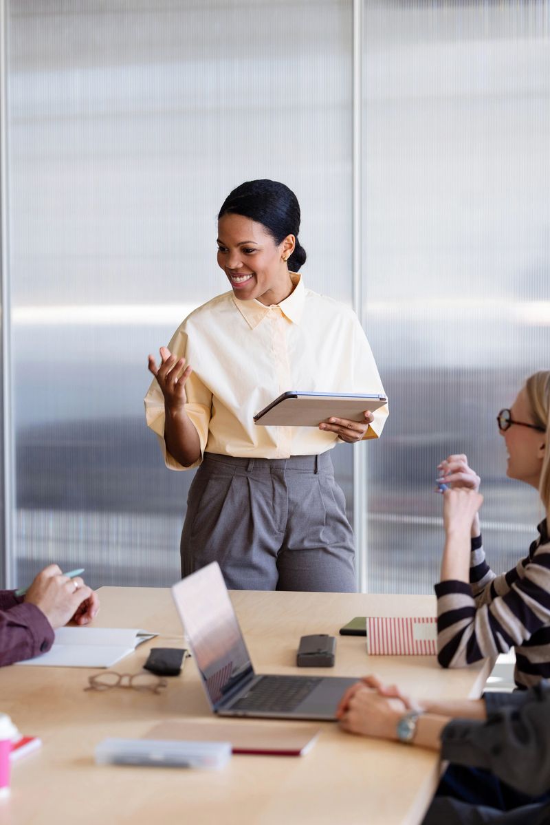 Confident businesswoman leads a small team meeting and presentation in a modern office boardroom.