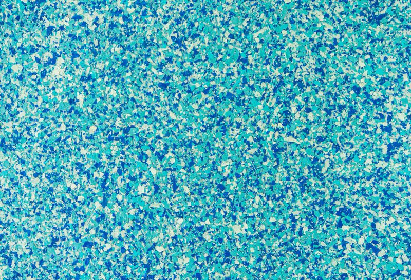 Abstract speckled texture background featuring a vibrant mix of light blue, dark blue, and white flakes. A seamless pattern perfect for modern graphic design and creative backdrops.