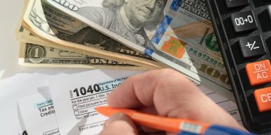 Filling out a 1040 U.S. tax form with money and a calculator nearby.