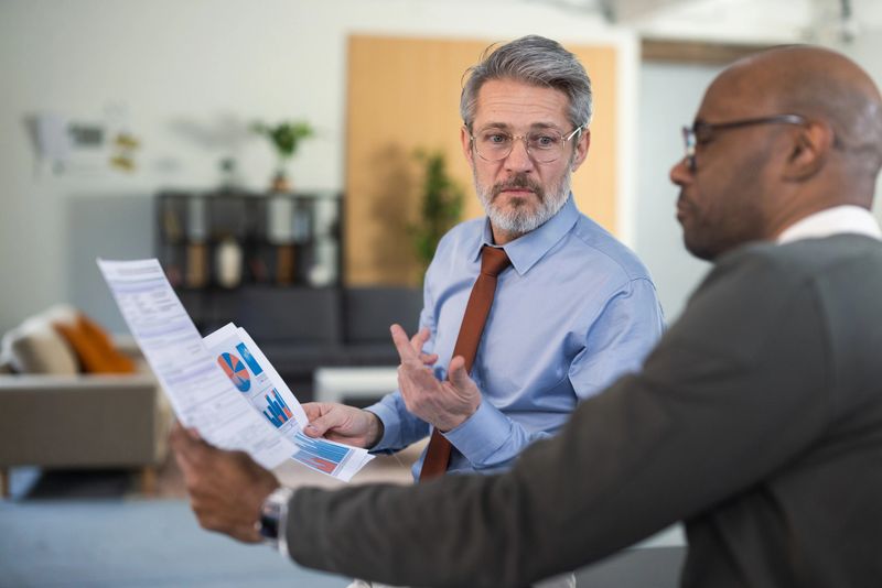 Two business colleagues discussing financial reports in a modern office meeting
