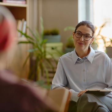 A woman with glasses attentively listening during a conversation indoors.