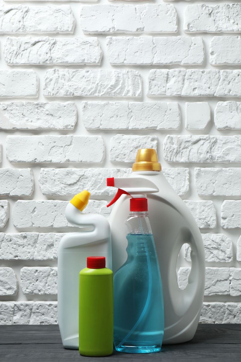 House cleaning supplies on a wooden table against a brick wall background