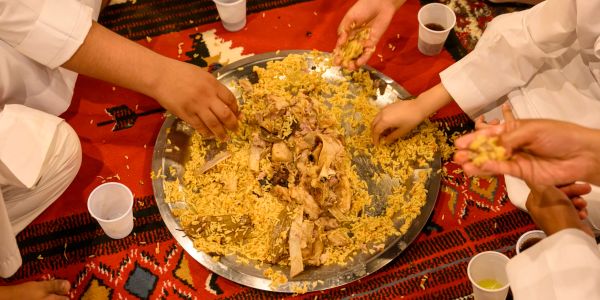 People sharing a traditional rice meal from a large tray.