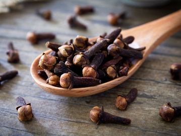 Close-up of cloves on a wooden spoon.