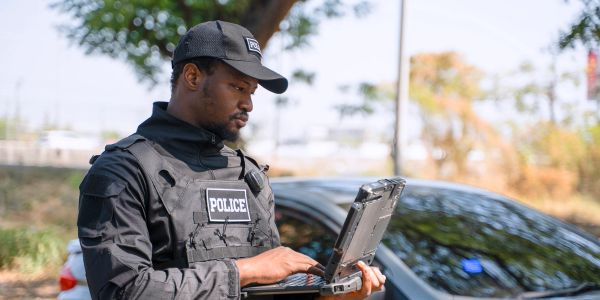 Police officer working on a laptop outdoors.
