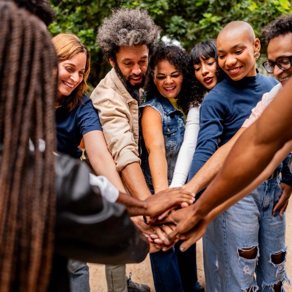 Diverse group forming a team huddle with hands joined.