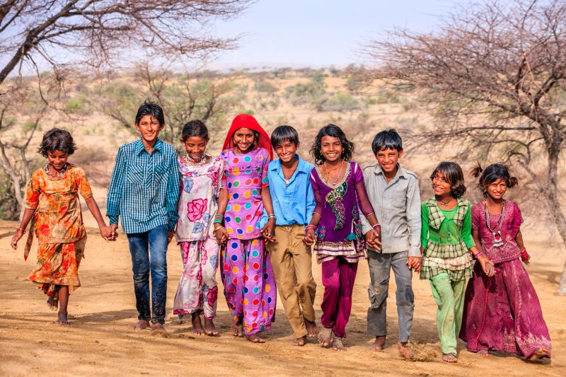 Group of happy Indian children walking together across sand dunes - desert village, Thar Desert, Rajasthan, India.