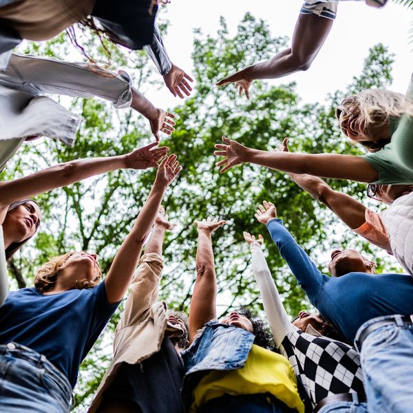 People standing in a circle reaching up.