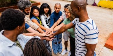 Group of diverse people joining hands in a huddle.