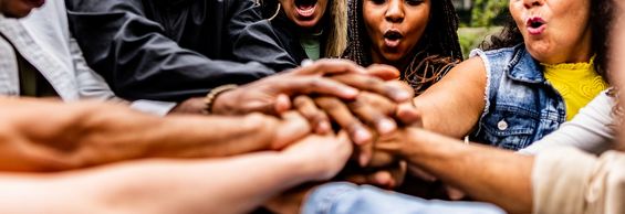 A group of people joining fists together in a circle.
