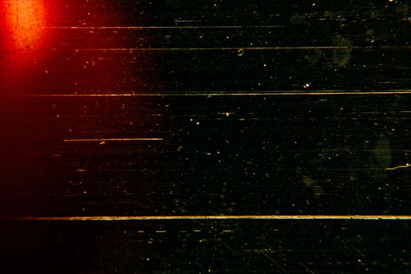 Abstract dark cinematic background with deep scratches and red light leak. Perfect for moody vintage film effects and creative grunge designs. Features artistic grain.