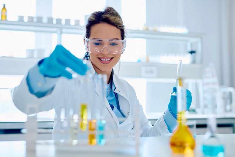 Young female conducting chemistry experiment, carefully pouring liquid into a test tube in a bright scientific lab