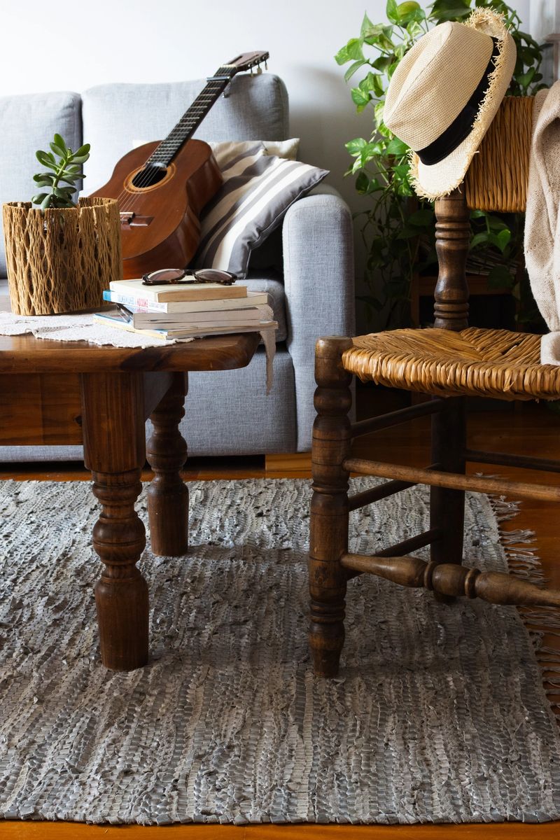 Vertical picture of an elegant living room interior with a wooden chair and coffee table, featuring some books and a brown guitar onthe sofa in the background. A perfect fit for magazines on interior design.