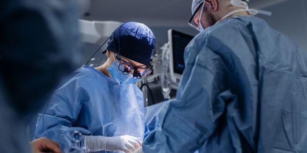 Surgeons in blue scrubs performing surgery in an operating room.