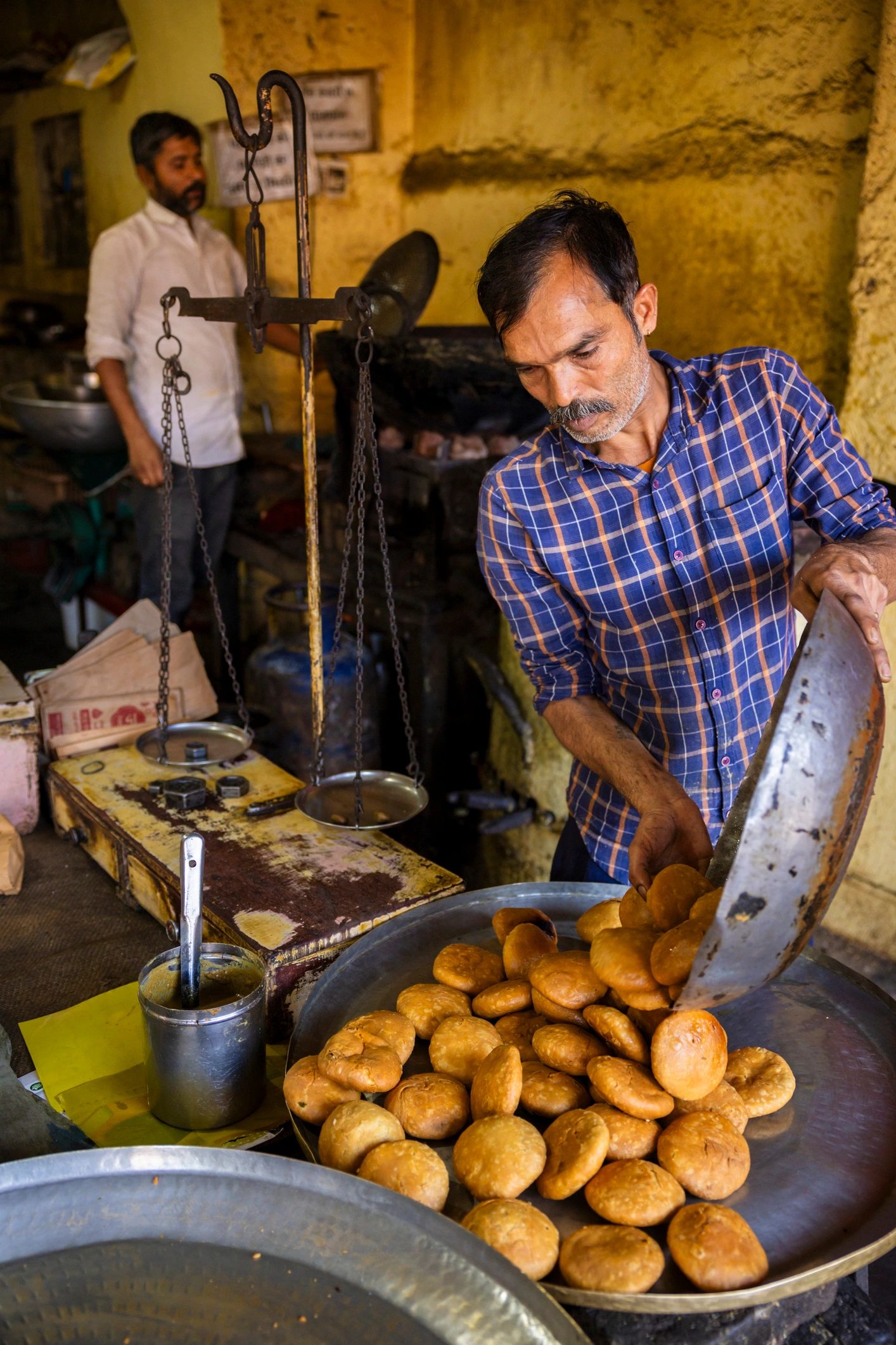 Man serving fried bread in a traditional Indian eatery.