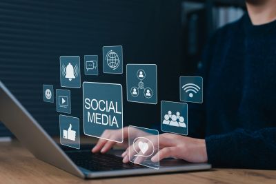 Person using a laptop with social media icons floating above.