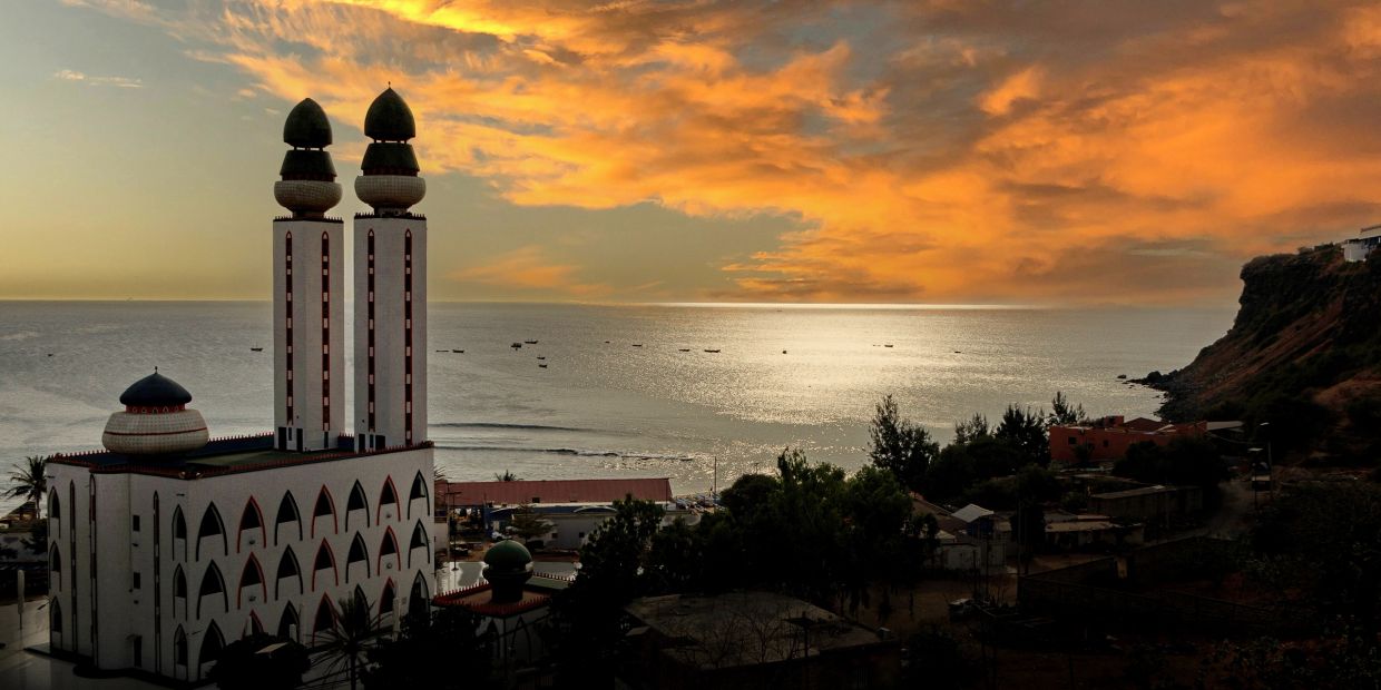 Mosque by the sea at vibrant sunset.