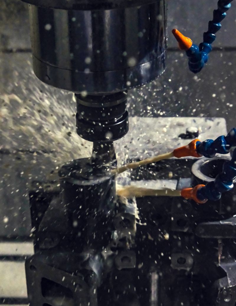 Modern industrial CNC machining process in intense action. Cutting fluid splashes dramatically. Highlighting the intense and efficient manufacturing process. Selective focus.