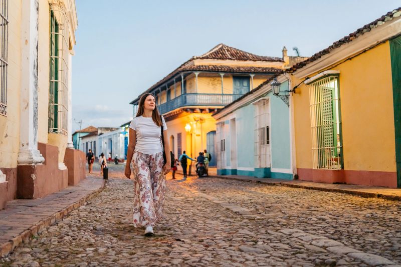 Beautiful young woman walking on the street in Trinidad in Cuba at dusk.