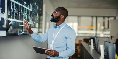 Man analyzing data on a large digital screen in a modern office.