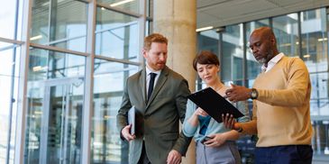 Three professionals discussing work in an office setting.