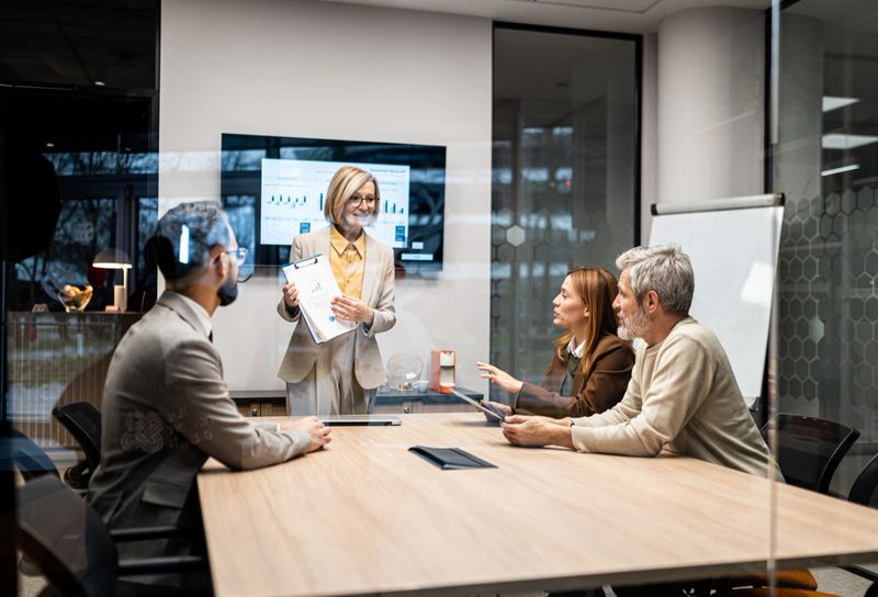 Confident businesswoman presenting charts and graphs to a team of diverse colleagues during a professional meeting in a modern conference room