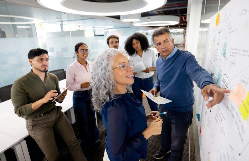 Happy group of Latin American people in a meeting brainstorming while designing a business plan