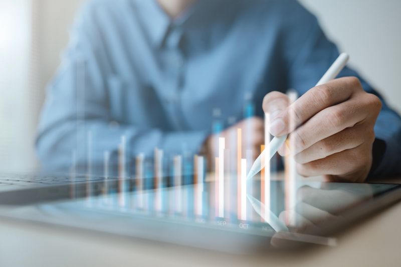 Business professional analyzing financial data on digital tablet with interactive chart dashboard, representing corporate strategy, KPI monitoring, financial analysis and business intelligence.