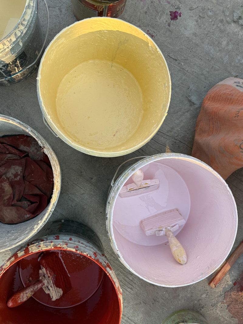 A collection of paint cans with different colors and one of them is yellow. The paint cans are arranged in a row, with the yellow one in the middle