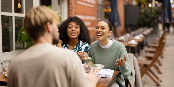 Three friends enjoying a lively conversation at an outdoor cafe.