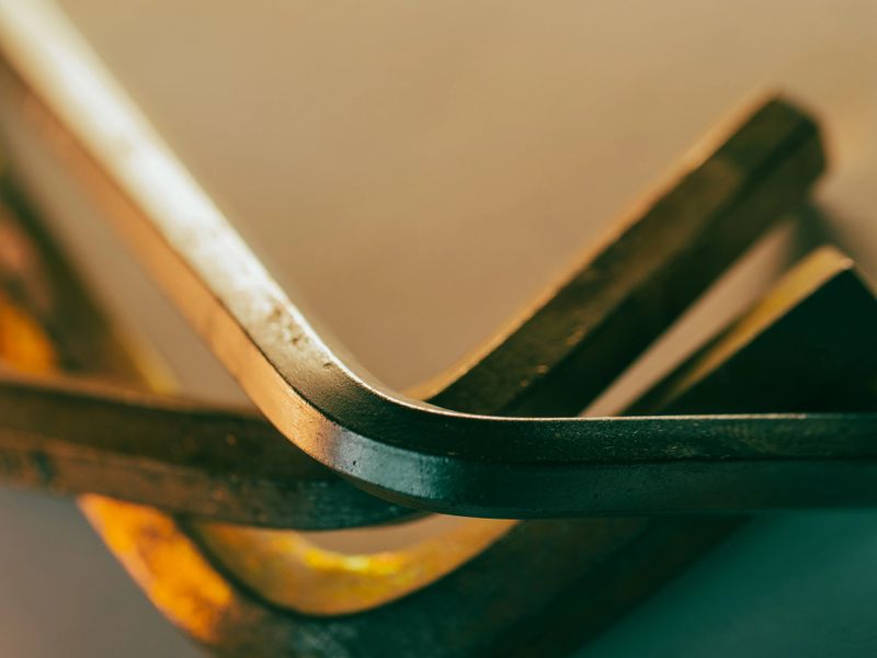 Metal edges gleam softly under warm light. Angles curve, hinting at precision and craftsmanship. Textures shift from polished to worn, suggesting use. Close-up detail captures industrial elegance