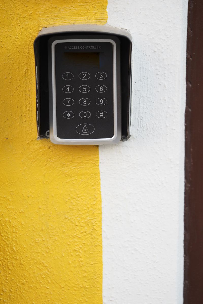 Close-up view of a keypad entry system on a yellow and white wall.