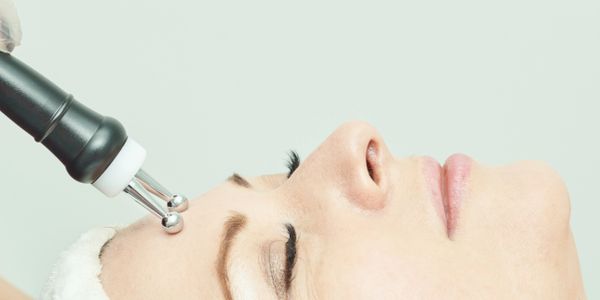 Woman receiving a facial treatment with a specialized device.