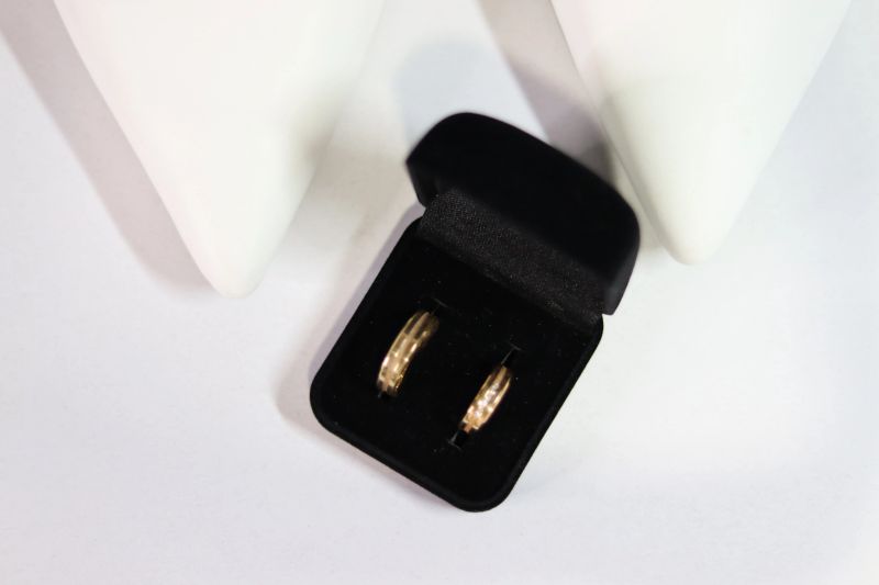 Close-up of two gold wedding rings inside a black velvet ring box placed on a white surface. Product-style photo suitable for jewelry, wedding, engagement or retail use.