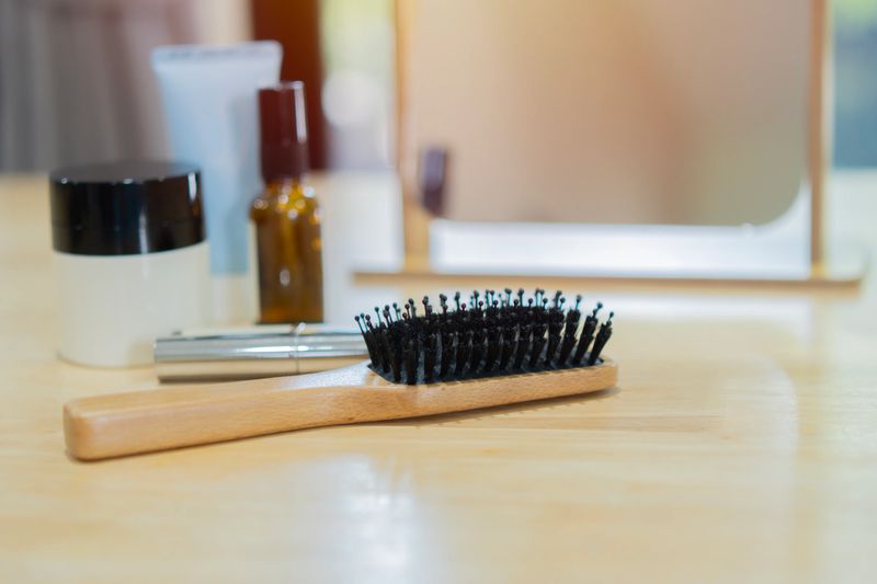 A wooden comb with cosmetic, mirror, makeup products and accessories on wooden table in room. Selective focus. Cosmetic concept.