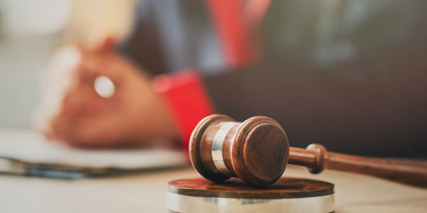 Wooden gavel on a block in a courtroom setting.