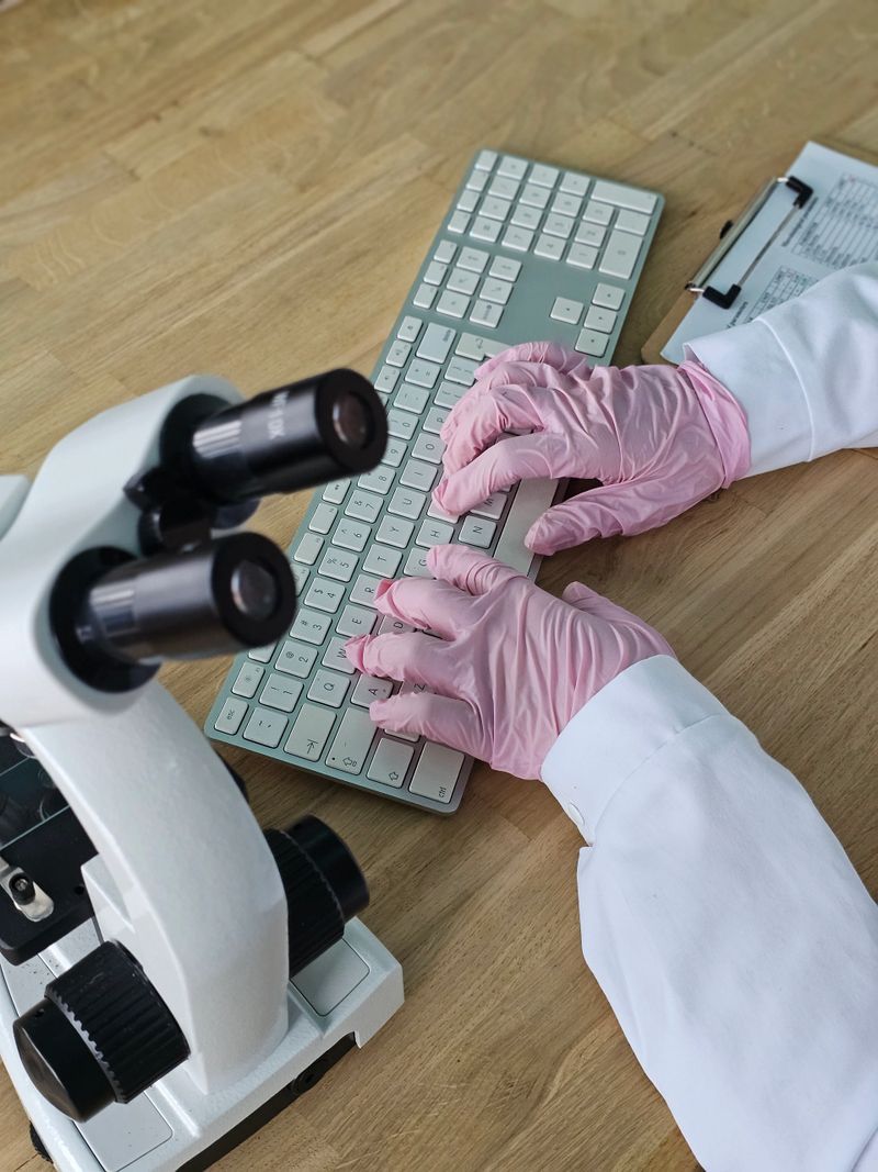 Scientist works at laboratory desk using microscope and keyboard during research project in modern lab setting